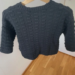 Svart stickad tröja från NA-KD - Säljer en svart stickad tröja från NA-KD med grov struktur och ribbad rund hals. Tröjan har långärmade ärmar och ett coolt rutigt stickmönster som ger den extra karaktär. Perfekt att matcha med jeans eller kjol för en chill look.