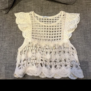 Vit spetsblus med volangärmar från Zara - ❗️storleken är M, men jag skulle säga att den är mer av en XS ❗️superfin vit blus från Zara med genombruten spets och broderade detaljer. Blusen har korta volangärmar med hålmönster och scallop-kant nedtill. Perfekt för dig som gillar romantisk och boho-inspirerad stil!