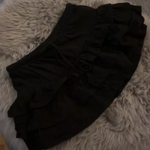 Svart volangkjol  - Svart volangkjol från Gina, aldrig använd då den är för kort på mig. Det är en mini kjol som är lågmidjad. 