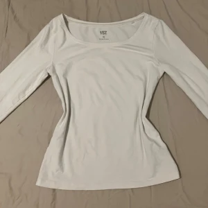 Vit långärmad topp från Lager 157  - En basic vit långärmad topp från 157 i storlek XS. Modellen har en rundad halsringning och har en bekväm stretchig känsla tack vare materialet i 95% bomull och 5% elastan. Kontakta om ni vill ha mått på någonting:)