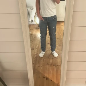 Levi's 511 blå jeans herr - Säljer ett par Levi's 511 jeans i klassisk blå färg med snyggt slitna detaljer framtill. Modellen är slim och har normal passform med raka ben. Jeansen har fem fickor, gul kontrastsöm och Levi's patch bak i midjan. Perfekta för dig som gillar en stilren och modern look. Passar mellan 155-165cm. Inga fel eller skavanker bara att höra av sig om man har funderingar!