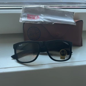 Svarta Ray-Ban Wayfarer solglasögon - Säljer ett par klassiska Ray-Ban Wayfarer solglasögon med svart, fyrkantig plastbåge och tonade linser. Kommer med originalfodral i brunt och putsduk. Perfekt för dig som vill ha en tidlös och cool look. 