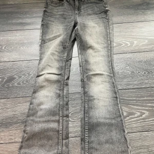 Grå bootcut jeans med slitning - bootcut jeans från Vero moda storlek  s/32 .använd 2 gånger så de är super fräscha och sitter jätteskönt! känns mer som tights än jeans. 
