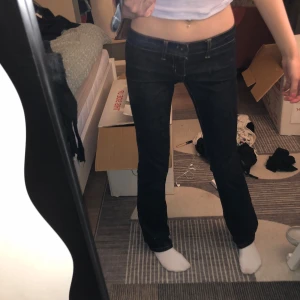 lågmidjade mörkblå jeans - Säljer ett par mörkblå jeans med låg midja och raka ben. Jeansen har klassiska kontrastsömmar och femficksmodell. Snygg passform som sitter tajt över höfterna och låren, och är lite rakare nertill. Perfekta till sneakers eller boots.