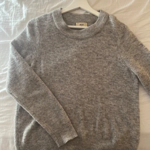 Grå stickad tröja från Object XS - Mysig grå stickad tröja från Object i storlek XS. Tröjan har rund hals, långa ärmar och ribbade muddar vid ärmslut och nederkant. Perfekt för dig som gillar enkel och stilren design. 