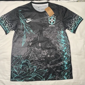 Brazil fotbollströja  - Snygg svart Brasil fotbollströja från Nike med coola turkosa detaljer, leopardmönster på ärmarna och grafiskt tryck av Rio de Janeiro och Kristusstatyn. CBF-emblem på bröstet, Dri-FIT material som andas och rund hals. Perfekt för dig som vill sticka ut på planen.