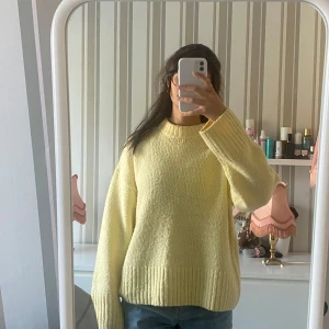 Ljusgul stickad tröja från gina - Mysig ljusgul stickad tröja med bred ribbad kant vid nederdel och ärmslut. Tröjan har en rund halsringning och långa ärmar med avslappnad, oversized passform. 