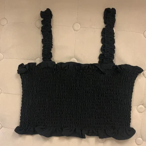 Svart linnetopp  - Supersöt svart linnetopp köpt från Zalando med smockad struktur och volangdetaljer både upptill och nedtill. Använd 1 gång så är i super bra skick. Storlek 36 men passar 34 också💗