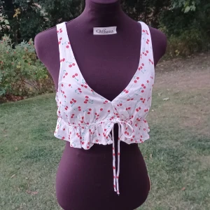 Vit croptop med körsbär - Supergullig croppad linnetopp från Zara med körsbärsmönster. Perfekt för sommaren🍒❤️💚 Ganska kort men knappt använd. Det är bara att skriva om man har frågor!😊💖