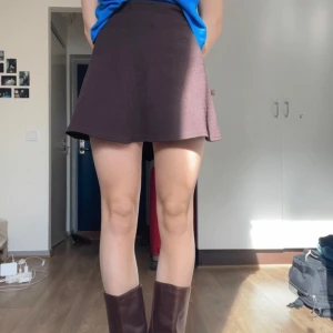 Brun kortkjol - Snygg brun kortkjol i en klassisk design. Perfekt för att matcha med olika toppar och accessoarer. Kjolen har en enkel och stilren look som passar till många tillfällen.