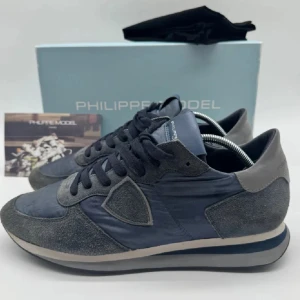 Grå sneakers från Philippe Model - Snygga blåa sneakers från Philippe Model med en stilren design. Storlek 42 men i vissa fall kan passa 43. Väldigt fint skick 9/10. Hör av er för fler bilder!