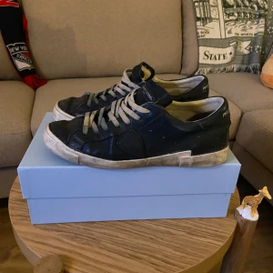 Mörkblå sneakers från Philippe Model - Snygga mörkblå sneakers från Philippe Model. Skorna är väl använda därav priset. Kvitto kan visas från online köpet ifall det önskas. Har vissa defekter och snörerna är lite avfärgade. Går att använda bra och är fortfarande väldigt snygga enligt mig men säljs pga köp av andra skor och dessa har hamnat i skymundan. Fråga ifall ni vill ha fler bilder och priset är diskuterbart.