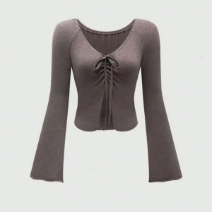 Grå ribbad topp med knytning - Snygg grå ribbad topp med långärmade utsvängda ärmar och knytning framtill. Perfekt för en stilren look.