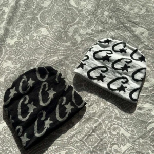 Svart och vit Cortiez mössa - Två stilrena mössor i svart och vit från märket Cortiez . Perfekta för att hålla värmen under kyliga dagar. Den svarta mössan har grått mönster medan den vita har svart mönster. Mössorna är helt nya och har knappt använd. En mössa för 175 kr två för 310 kr.