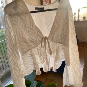 Vit blus från Shein - Säljer en elegant vit blus från Shein med ett subtilt mönster och knytning framtill. Blusen har långa ärmar och en luftig passform, perfekt för en stilren look. Passar bra till både jeans och kjol. 🌟