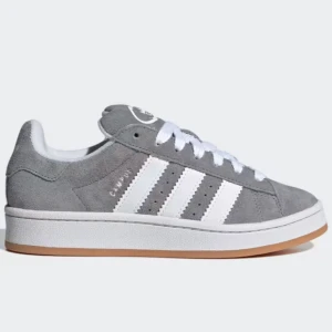 Adidas Campus - Snygga grå Adidas Campus sneakers i mocka med vita detaljer och klassiska tre ränder på sidan. Skorna har en vit sula med en gummifärgad undersida och snörning framtill. Perfekta för en stilren och avslappnad look.