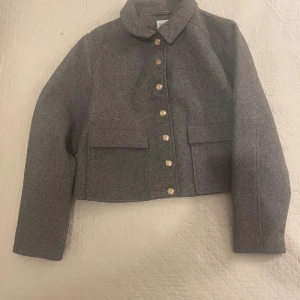 Grå jacka från Zara - Säljer en stilren grå jacka från Zara med eleganta guldknappar. Jackan har en croppad passform och långa ärmar. Perfekt för att ge en sofistikerad touch till din outfit. 🖤