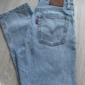 Levis jeans i ljusblå denim strl 23 - Snygga Levis jeans i en ljusblå denimfärg. Modell: 501 med en bekväm passform. Perfekta för en avslappnad stil. Märkeslappen syns tydligt på baksidan. Strl: 23/26