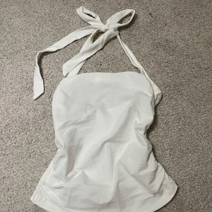 Vit topp - Vit topp med knytning i nacken och dubbeltyg på framsidan. Litet märke vid knytningen. 
