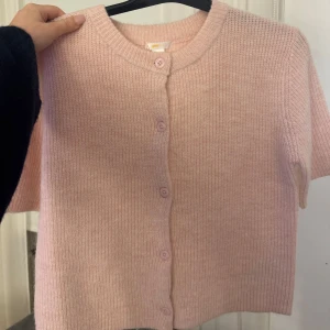 Rosa kofta - Säljer en söt rosa kofta från Gina Tricot. Den är stickad med korta ärmar och har knappar framtill. Perfekt för en mysig och stilren look. 💖använd 1-2 ggr