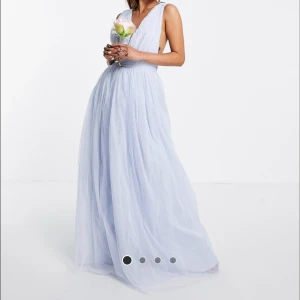 Ljusblå balklänning  - Elegant ljusblå klänning med v-ringning och djup rygg, har gjorts om till en rosett, går att ändra tillbaka (sista bilden). Endast använd 2 gånger och i bra skick, superfin som balklänning! Slutsåld på hemsidan just nu. Fler bilder finns!!