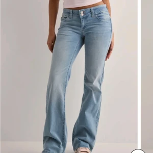 Blå bootcut jeans - Snygga ljusblå bootcut jeans med låg midja och broderade detaljer på bakfickorna från Nelly.  Helt nytt skick,  endast använda två gånger. Passar lite kortare personer som är ca (160-164) då jag sytt upp längden på jeansen. Ord pris 700kr