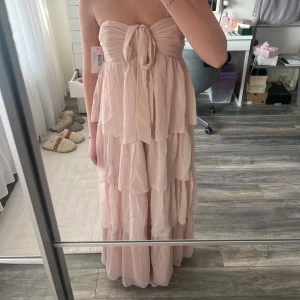 Ljusrosa axelbandslös klänning - Säljer denna underbara balklännigen  från Nelly då det inte var min färg💕 klänningen är aldrig använd endast provad och har alla prislappar kvar! Ny pris är 700kr💕