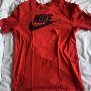 Röd t-shirt från Nike - Snygg röd t-shirt från Nike med det klassiska logotyptrycket i svart på framsidan