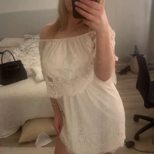  spetsklänning - Säljer en söt beige spetsklänning med offshoulder-design. Klänningen har ett vackert  mönster och är perfekt för sommaren. Finns någon fläck på inner klänningen men inget som syns när man har på sig klänningen