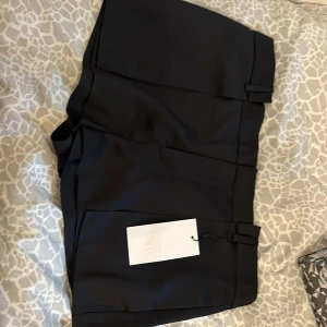Svarta kostymshorts från Zara - Snygga svarta shorts från Zara med en stilren design. Perfekta för en chic look. De har en hög midja och är tillverkade i ett bekvämt material som passar bra till olika tillfällen. Helt nya