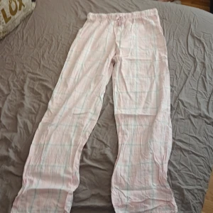 Rosa rutiga byxor från Gina Tricot - Mysiga rosa byxor med rutigt mönster från Gina Tricot. De har en elastisk midja för extra komfort och är perfekta för en avslappnad dag hemma. Byxorna är tillverkade i ett mjukt material som känns skönt mot huden.