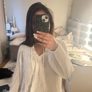 Vit blus med knytband - Säljer en luftig vit blus med v-ringning och knytband framtill. Blusen har långa ärmar och en avslappnad passform, perfekt för en stilren look. Pris kan diskuteras 💞