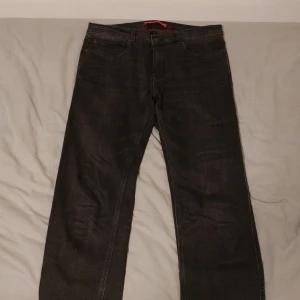 Mörkgråa jeans från Hugo - Mörkgråa jeans från Hugo med en unik design på baksidan av midjan där det står Hugo med vit text. 