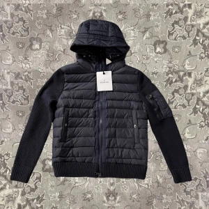 Svart jacka från Moncler - Snygg svart jacka från Moncler med quiltad design och huva. Jackan har dragkedja framtill och ribbade ärmar. Perfekt för kyligare dagar med sin stilrena look och praktiska fickor.