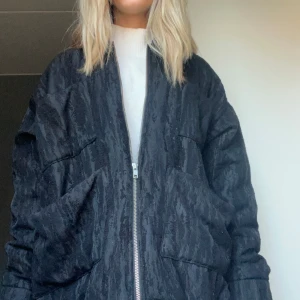 Svart bomberjacka - Snygg svart bomberjacka med dragkedja framtill. Jackan har en cool textur och en avslappnad passform. Perfekt för att ge din outfit en edgy touch.