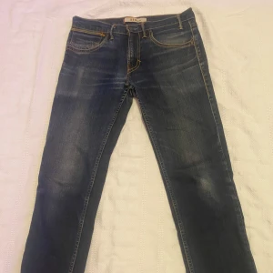 Blå jeans från Levi's - Snygga blå jeans från Levi's med klassisk femficksdesign och kontrastsömmar. Perfekta för en avslappnad stil. De har en knappgylf och är i en tidlös blå färg.