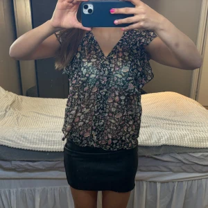 Blommig blus med volangdetaljer - Säljer en söt blommig blus med volangdetaljer och v-ringning. Blusen har korta ärmar och ett luftigt fall, perfekt för varmare dagar. Köptes från Zalando och är endast använd ett fåtal gånger. Säljer pga att den inte kommer till använding. Strl S/36