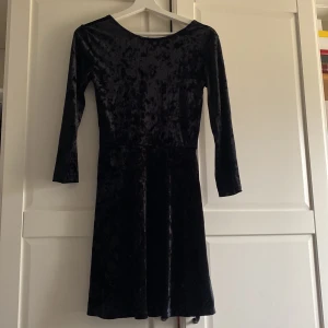 Svart sammet klänning - Snygg svart klänning i mjukt sammetstyg. Klänningen har en klassisk passform och är knälång.