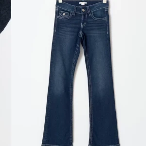 Chunky low flare jeans - Snygga mörkblå bootcut jeans med kontrastsömmar och femficksdesign. Jeansen har en låg midja och en klassisk dragkedja med knapp. Perfekta för en avslappnad stil. Säljer då de är för små, använd fåtal gånger! Från Gina Young