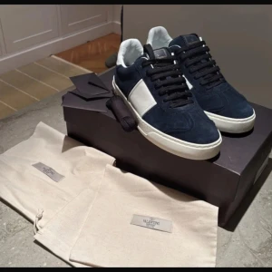 Valentino sneakers i blå mocka - Snygga Valentino sneakers i blå mocka med vita detaljer. Skorna har en rund tå och klassisk snörning. Perfekta för en stilren look.