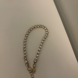 Armband med stenar rostfritt stål - Snyggt armband med glittrande stenar som ger en elegant touch. Perfekt för att lyfta vilken outfit som helst. Armbandet har en guldfärgad kedja och en säker låsning.