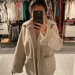 Beige teddyjacka - Sååå mysig och trendig beige teddyjacka med långa ärmar och knappar framtill. Perfekt för kyliga dagar med två stora fickor framtill. Passar året runt och är så snygg, varm och mysig. Från H&M i storlek XS, har även en röd fläck som knappt syns, visar på sista bilden, inte försökt få bort den dock!🥰