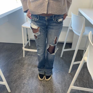 Blå jeans med slitningar - Säljer ett par blå jeans med slitningar och hål på framsidan. Lappade mellan benen men har slitningar, kan skicka bild, hör av dig privat om du vill ha bild.