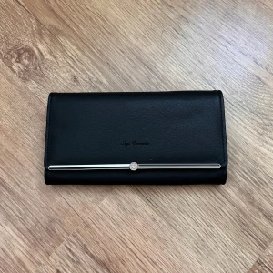 Svart plånbok med hjärtformad detalj - Elegant svart plånbok med en stilren design och en hjärtformad detalj inuti. Plånboken har flera kortfack och en knappstängning. Perfekt för att hålla ordning på dina kort och kontanter.