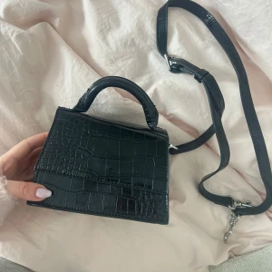 Svart axelväska i syntet - Snygg svart väska. Väskan har ett justerbart axelband och ett praktiskt innerfack. Perfekt för att bära med sig det viktigaste. Stilren och enkel att matcha med olika outfits💓💓 nypris 400kr