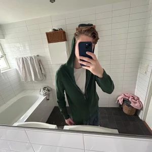 Grön hoodie 100% cashmere - Säljer en skön grön hoodie från Lawrence i 100% cashmere med dragkedja framtill. Perfekt för kyliga dagar. Den har långa ärmar och en praktisk huva. Passar bra till jeans eller avslappnade byxor.