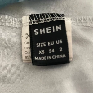 Blå mönstrad klänning från Shein - Snygg blå klänning från Shein med ett unikt mönster i grönt och blått. Klänningen har en slits på sidan och smala axelband. Perfekt för en somrig look!