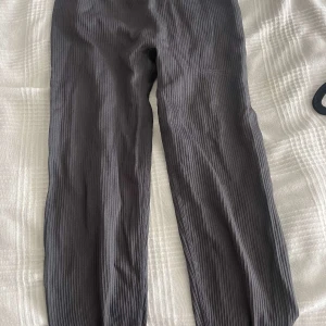 Grå träningsbyxor från New Apparel - Snygga grå ribbade byxor från New Apparel i storlek S. Byxorna har en bekväm passform och är perfekta för en avslappnad stil. De är tillverkade i ett mjukt material som ger en skön känsla hela dagen.