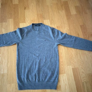 Grå tröja från J.Lindeberg - Säljer en stilren grå tröja från J.Lindeberg. Tröjan har en klassisk rund hals och långa ärmar. Perfekt för en avslappnad eller uppklädd look. Nästan nyskick och inga som helst defekter. Nypris 1200kr