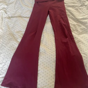 Vinröda byxor med utsvängda ben - Snygga vinröda byxor med utsvängda ben, som yoga pants. Perfekta för en trendig look. Byxorna har en hög midja som går att vika ner och är tillverkade i ett mjukt material som ger en bekväm passform. Pris går att diskuteras. Byxorna har ett hål som knappast syns.